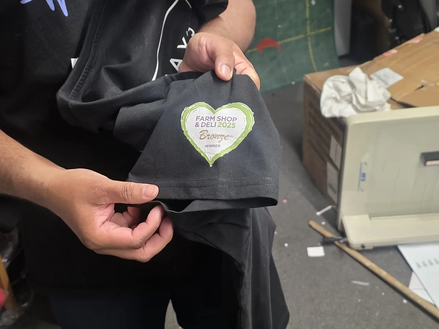 Farm Shop & Deli 2025 award badge printed on a t-shirt sleeve by IT Wheel London